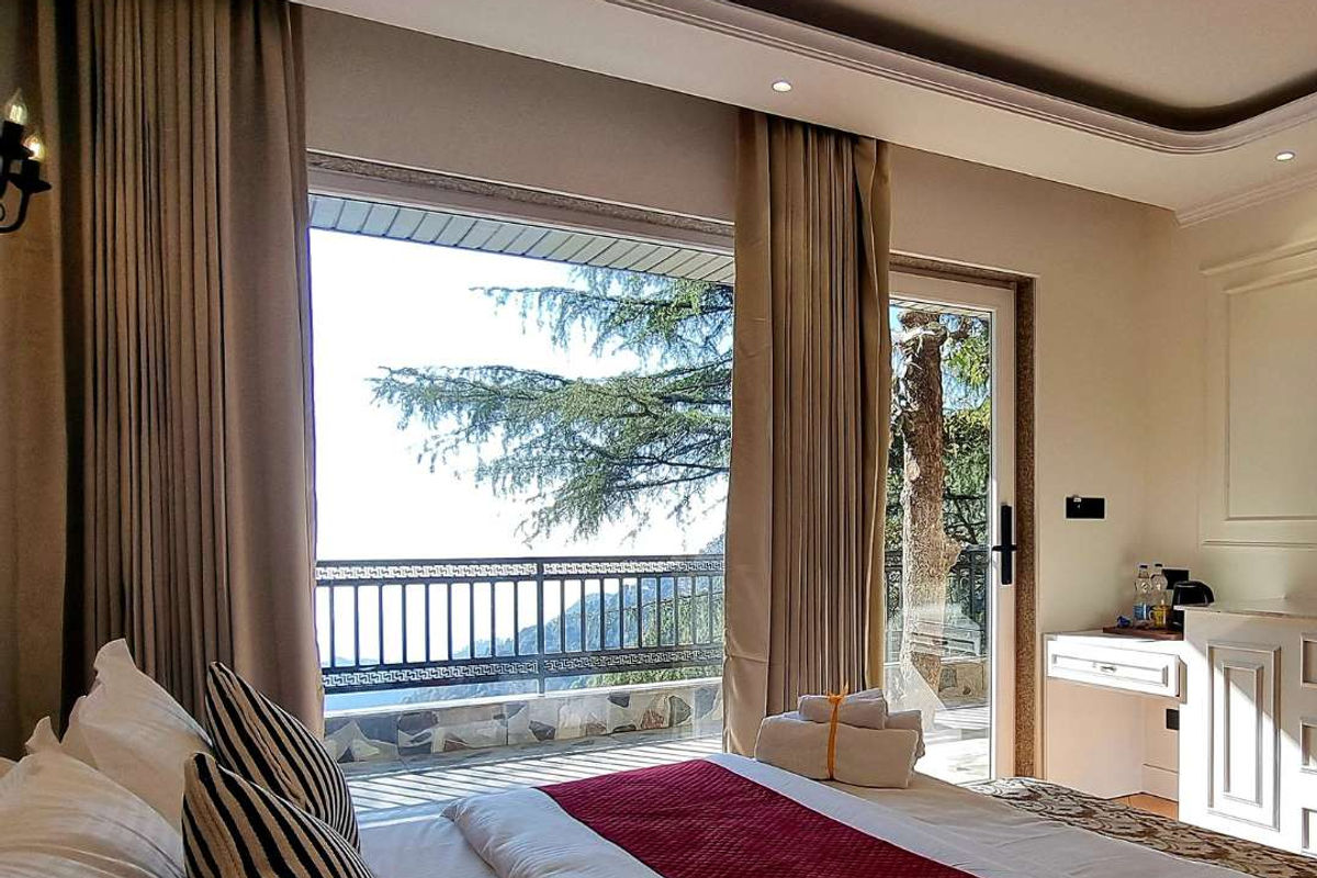 Executive Room at Akasa Dalhousie, king bed with open balcony door and pine tree mountain valley views